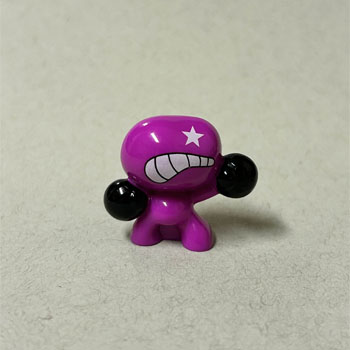 The toy is small and collectible, featuring a magenta body with two black spherical hands.